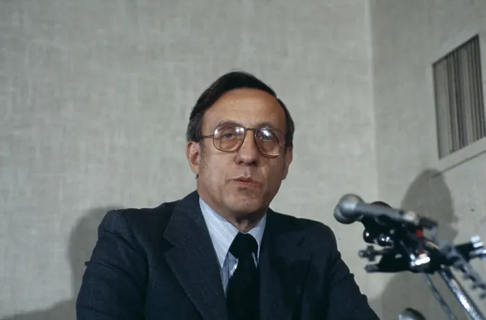 Portrait of Donald P. Jacobs at a microphone.